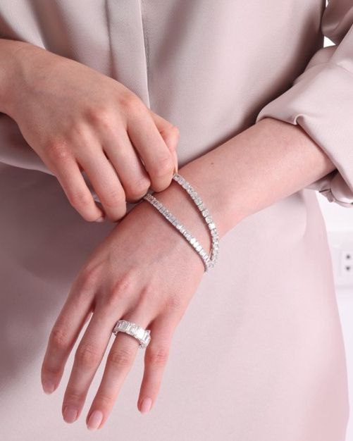 Model wearing diamond tennis bracelets and a ring